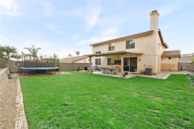 back of house with stucco siding, a trampoline, a fenced backyard, a yard, and cooling unit