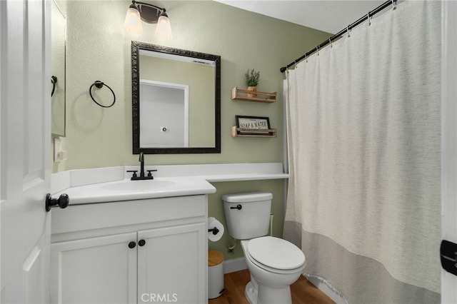 full bathroom featuring vanity, toilet, wood finished floors, and a textured wall