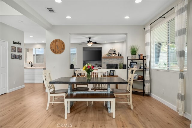 dining area with light wood-style flooring, a fireplace, and baseboards