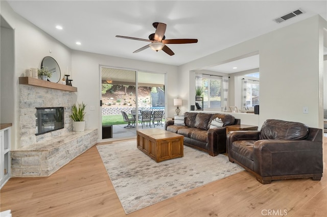 living room featuring a ceiling fan, visible vents, light wood-style flooring, recessed lighting, and a fireplace