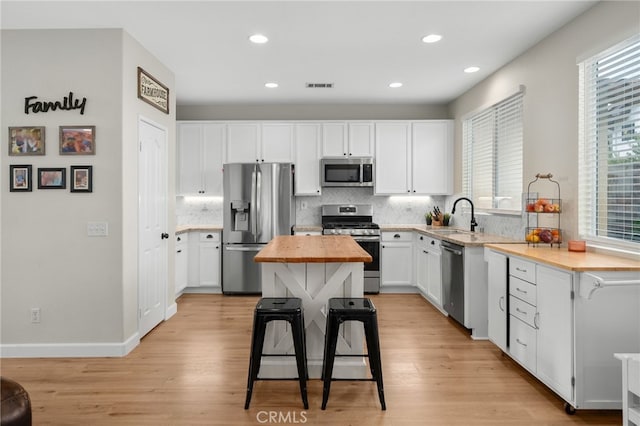 kitchen featuring a sink, wood counters, appliances with stainless steel finishes, and a healthy amount of sunlight