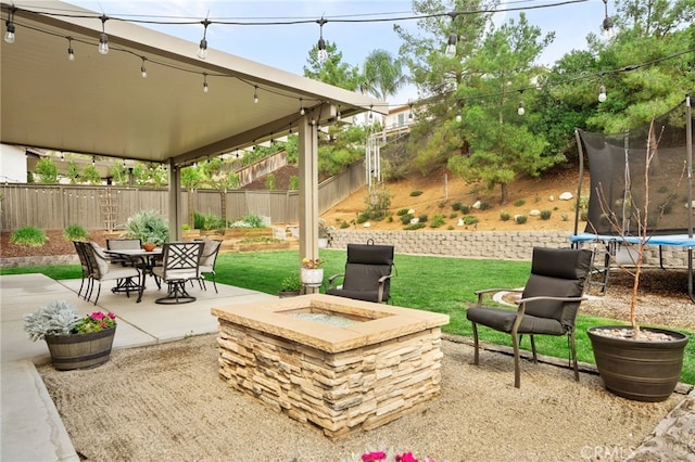 view of patio / terrace with a trampoline, a fire pit, and a fenced backyard