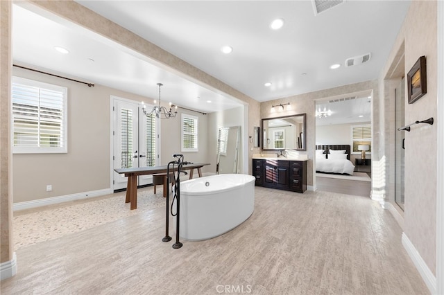 bathroom with ensuite bath, a freestanding tub, wood finished floors, and visible vents