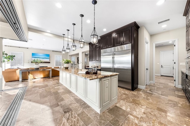 kitchen with stainless steel built in refrigerator, visible vents, recessed lighting, and light stone counters