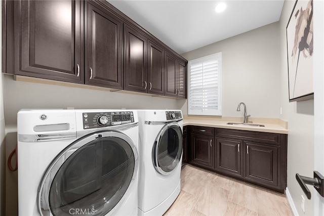 laundry area featuring washer and dryer, cabinet space, and a sink