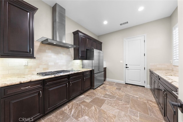 kitchen featuring baseboards, visible vents, stainless steel appliances, dark brown cabinetry, and wall chimney exhaust hood