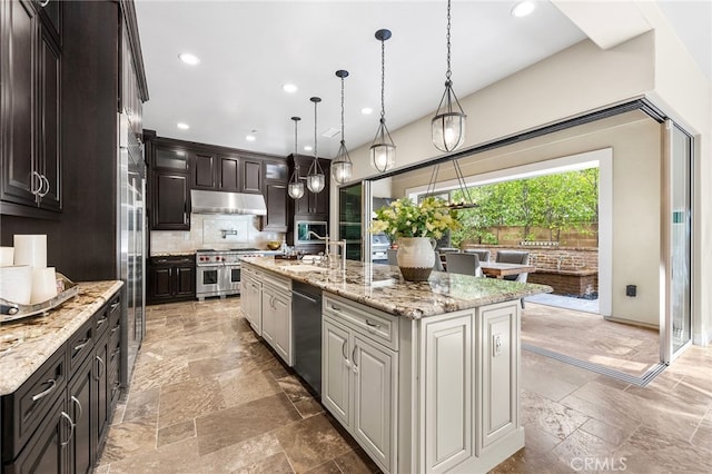 kitchen featuring under cabinet range hood, stainless steel appliances, tasteful backsplash, and stone tile flooring