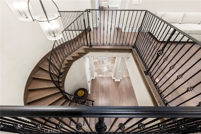 stairs with an inviting chandelier and wood finished floors