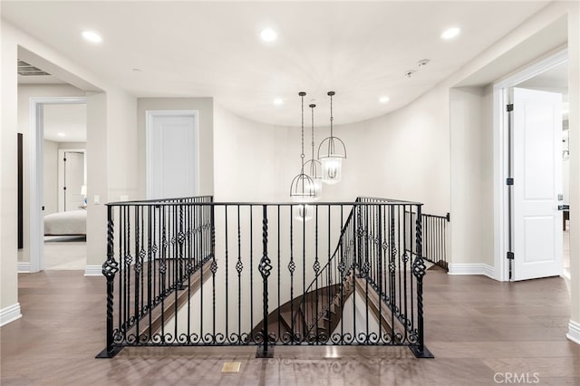 corridor featuring an upstairs landing, a notable chandelier, and wood finished floors