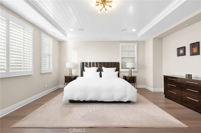 bedroom with a tray ceiling, dark wood-style floors, and baseboards