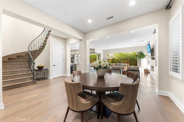 dining area with visible vents, baseboards, wood finished floors, and stairway