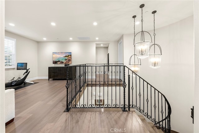 stairway featuring a chandelier, recessed lighting, baseboards, and wood finished floors