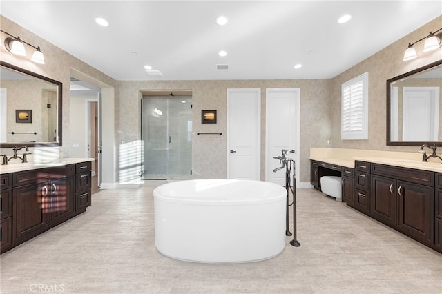 bathroom featuring visible vents, two vanities, a stall shower, a sink, and a freestanding bath