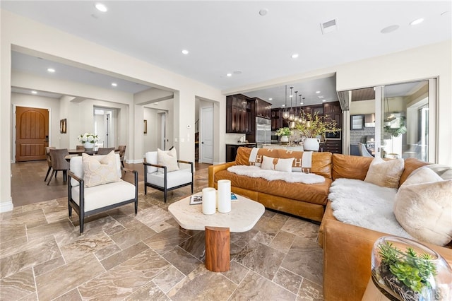 living area featuring stone finish floor, recessed lighting, visible vents, and baseboards