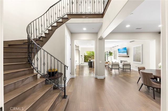 foyer featuring a towering ceiling, stairs, baseboards, and wood finished floors