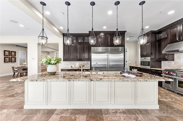 kitchen with under cabinet range hood, premium appliances, dark brown cabinetry, and a sink