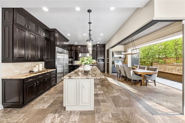 kitchen featuring backsplash, light stone countertops, built in appliances, pendant lighting, and recessed lighting