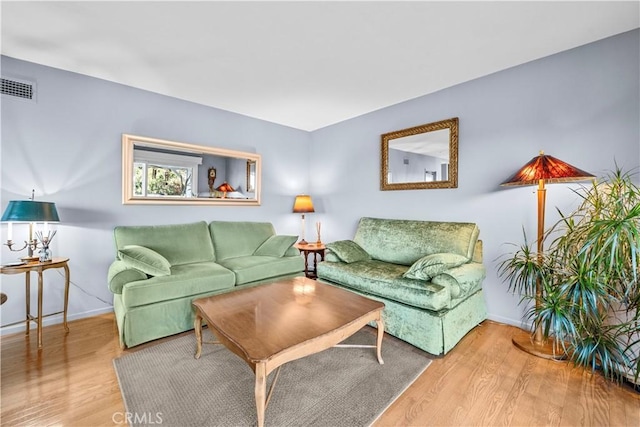 living room with visible vents, baseboards, and wood finished floors