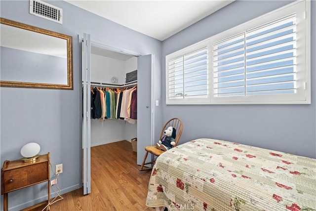 bedroom with visible vents, a walk in closet, baseboards, light wood-type flooring, and a closet