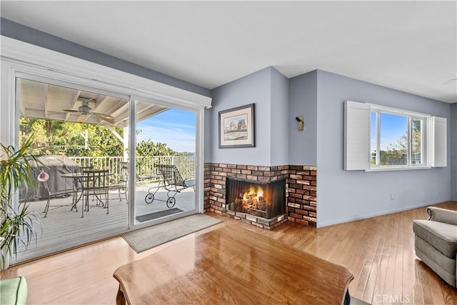 living area featuring a ceiling fan, wood finished floors, and a fireplace