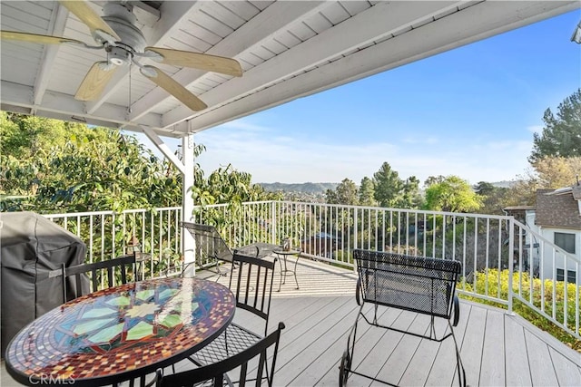 wooden deck with outdoor dining area, grilling area, and a ceiling fan