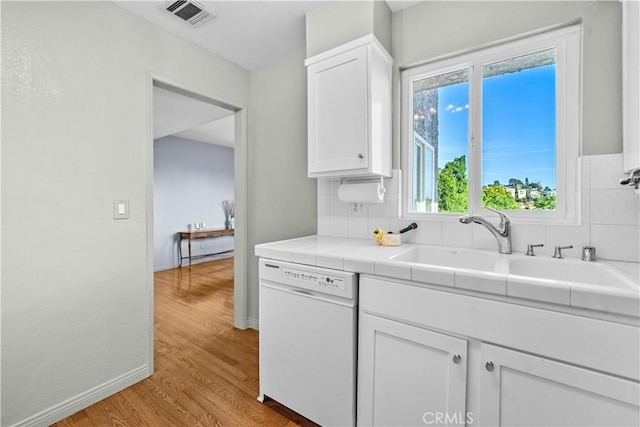 kitchen featuring visible vents, tile counters, dishwasher, light wood-type flooring, and white cabinets