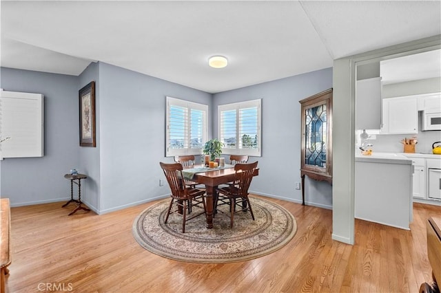 dining space with baseboards and light wood finished floors