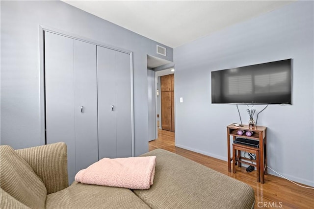 bedroom with a closet, baseboards, light wood-style floors, and visible vents