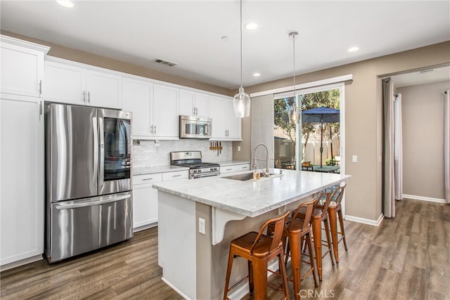 kitchen with dark wood-style floors, a sink, decorative backsplash, stainless steel appliances, and white cabinets