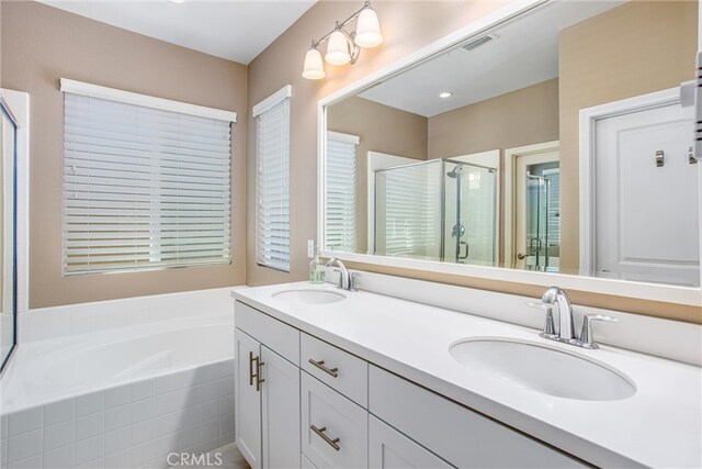 bathroom featuring a sink, visible vents, a bath, and a shower stall