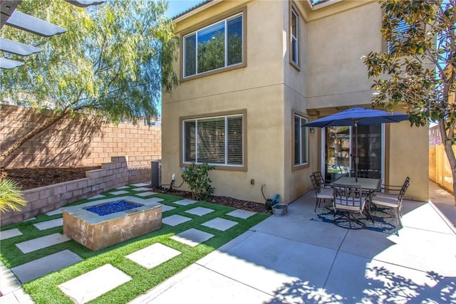 rear view of house featuring a patio area, stucco siding, an outdoor fire pit, and fence