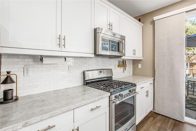 kitchen with backsplash, white cabinets, stainless steel appliances, and dark wood-type flooring