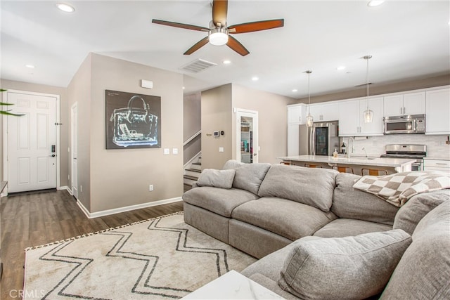 living area featuring visible vents, baseboards, recessed lighting, dark wood-style flooring, and stairs