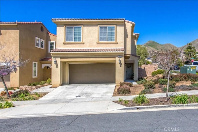 view of front of house with a tile roof, a mountain view, driveway, and stucco siding