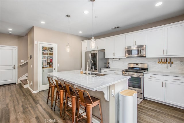 kitchen with tasteful backsplash, visible vents, dark wood finished floors, stainless steel appliances, and a sink