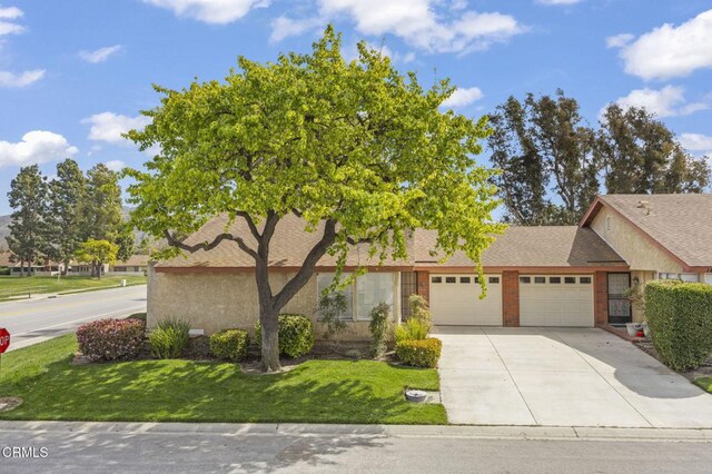 view of front of house featuring concrete driveway, a garage, a front yard, and roof with shingles