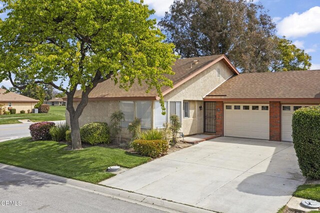 view of front of home featuring stucco siding, a front lawn, roof with shingles, and an attached garage