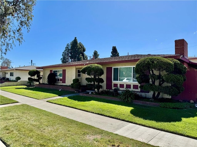 ranch-style home featuring stucco siding, a chimney, and a front lawn