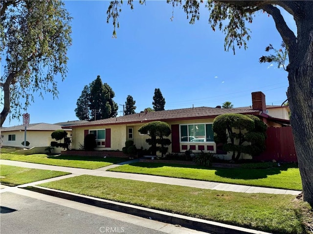 ranch-style home with a front yard and fence