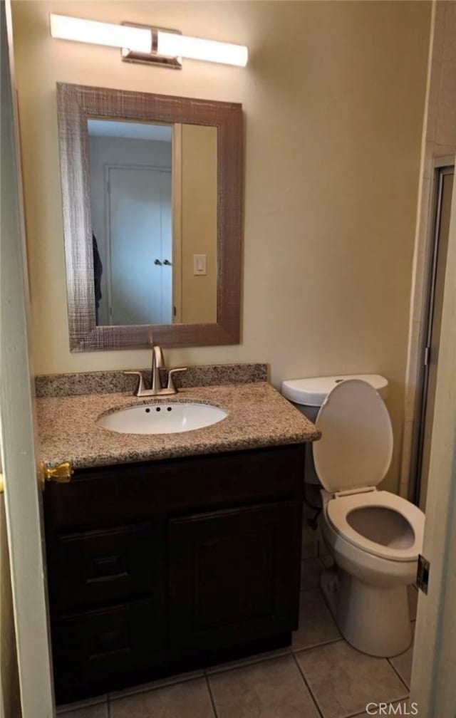 bathroom featuring toilet, vanity, and tile patterned flooring