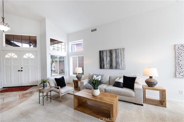 carpeted living room with visible vents, a high ceiling, and baseboards