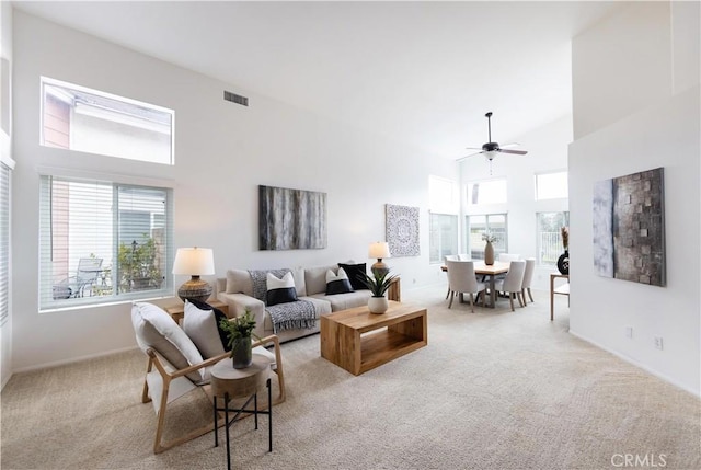 carpeted living room featuring visible vents, baseboards, high vaulted ceiling, and a ceiling fan