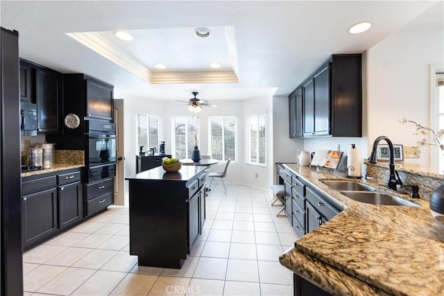 kitchen with a raised ceiling, black oven, light tile patterned floors, and a sink