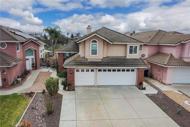 traditional-style house featuring stucco siding, concrete driveway, a garage, brick siding, and a tiled roof