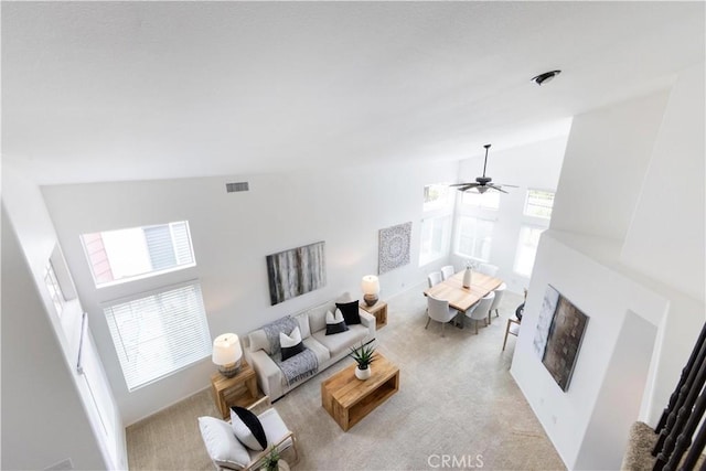 carpeted living room featuring visible vents, a fireplace, and high vaulted ceiling