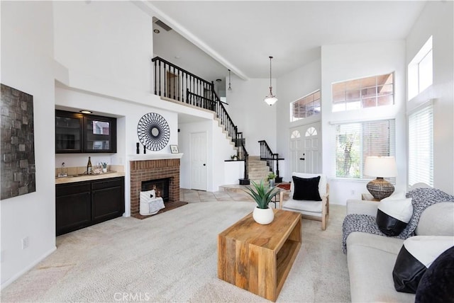 living area with stairway, light carpet, indoor wet bar, a fireplace, and a high ceiling