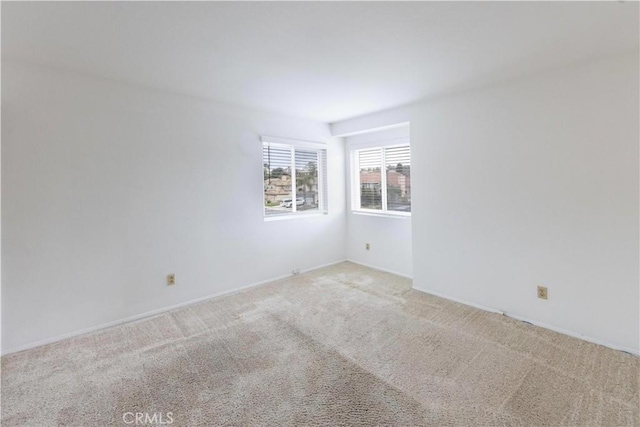 spare room featuring baseboards and light carpet