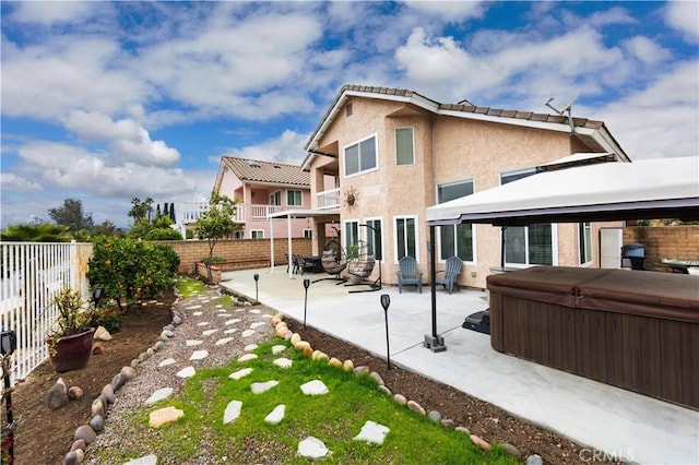 rear view of house featuring a patio area, a fenced backyard, a hot tub, and stucco siding