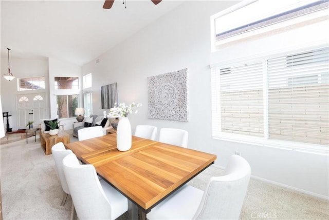 dining room with light carpet, baseboards, high vaulted ceiling, and a ceiling fan