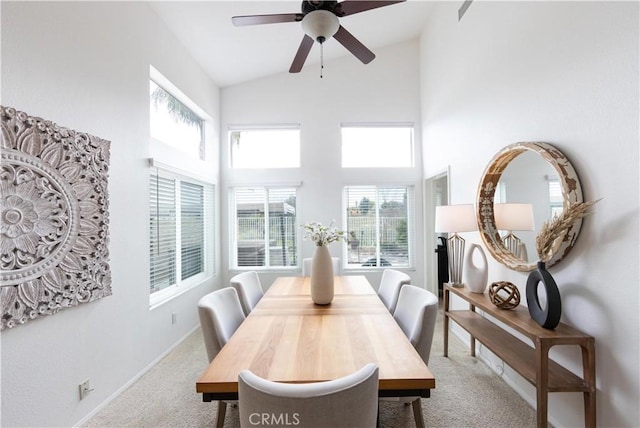 carpeted dining area with baseboards, high vaulted ceiling, and a ceiling fan